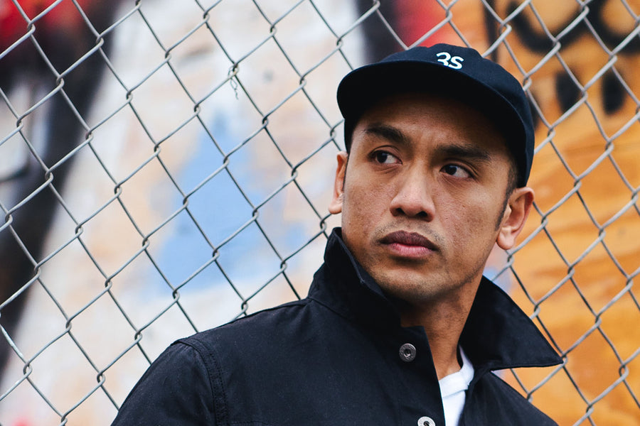 A portrait of a man in a waxed canvas jacket and black cap.