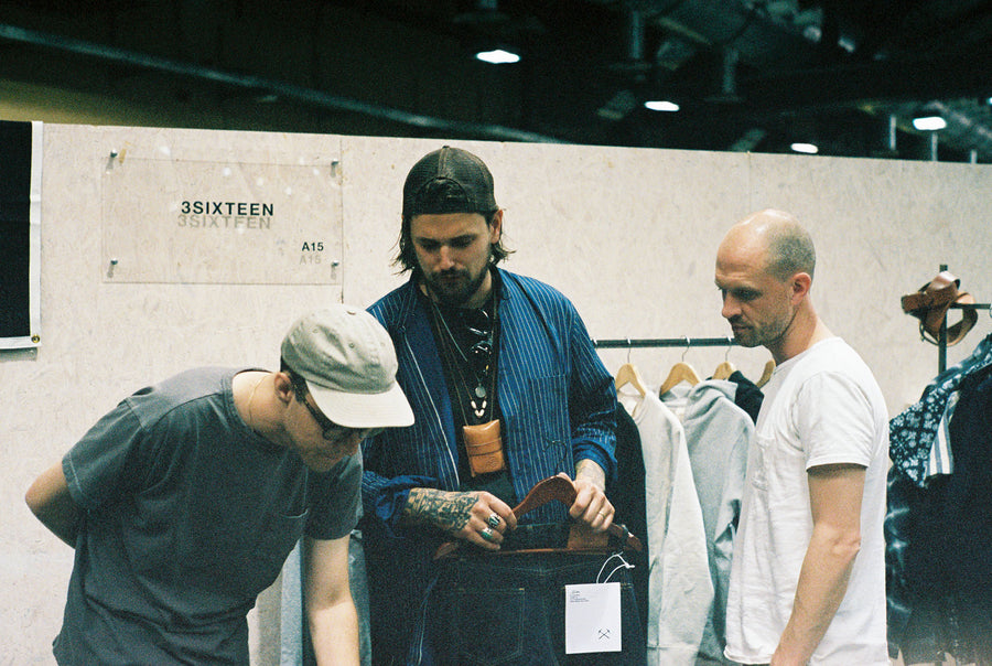 Three men discuss important things inside a tradeshow booth.