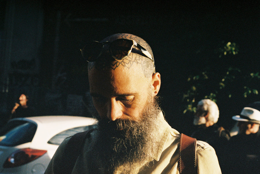 A man with a tattooed scalp in the sunset.