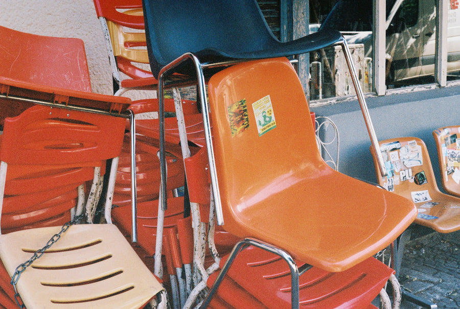 Orange chairs are stacked and chained together.