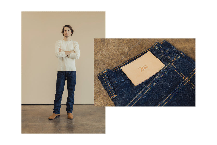 A man in a thermal and blue jeans stands on a concrete floor