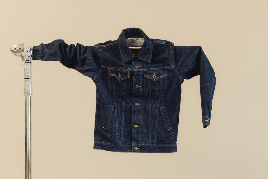 A denim jacket hangs on a horizontal pole.