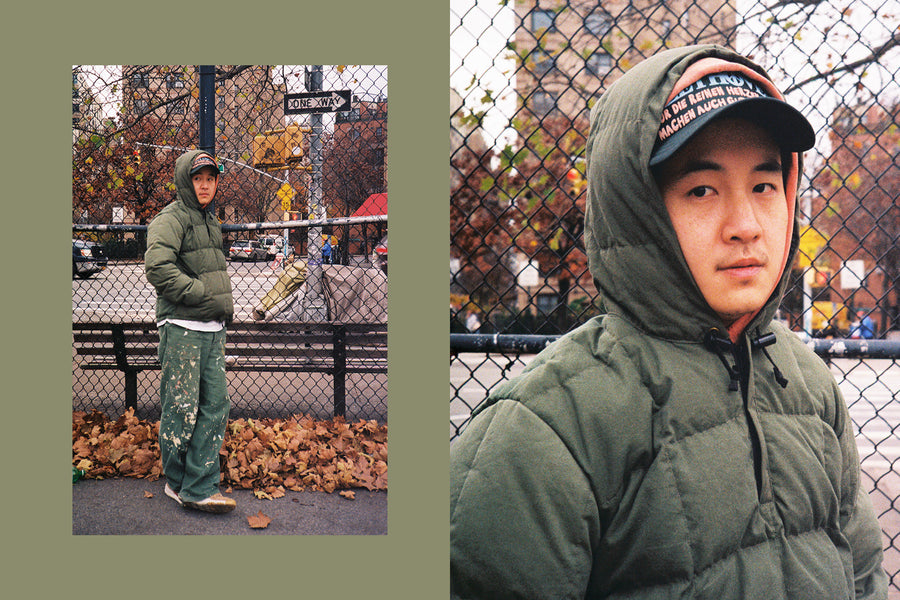 A young man wears the down jacket with paint splattered fatigues.