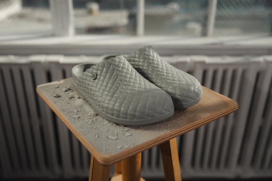 A pair of grey mules sit on a wooden base with dust around it.