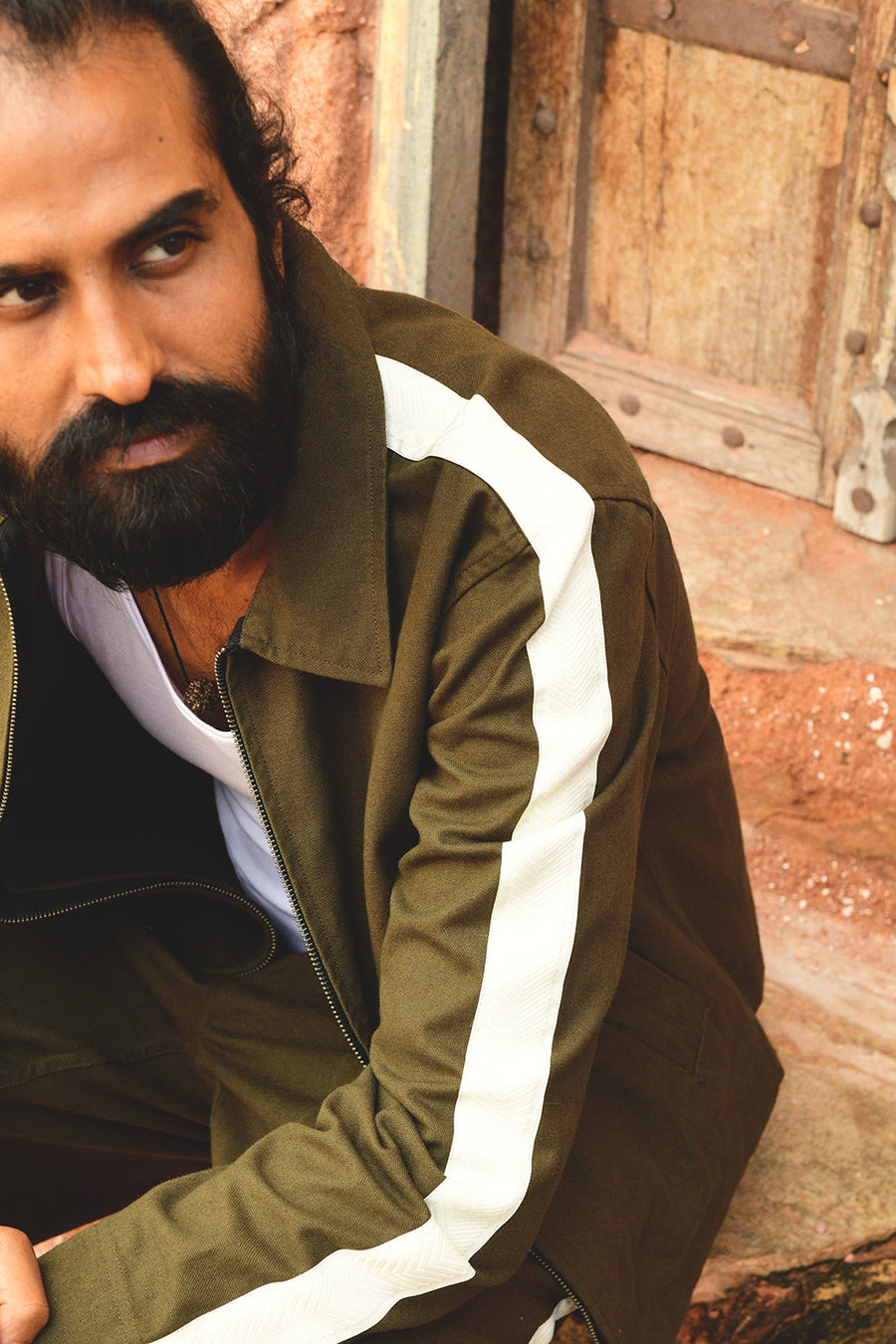 A closeup shot of a man in a green jacket with a cream stripe running down the sleeve.