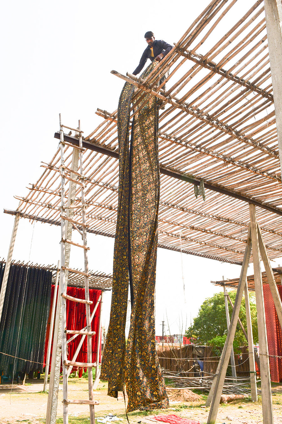 A gigantic roll of fabric is hung off of bamboo scaffolding to dry.