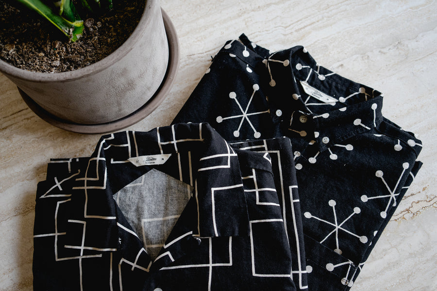 Two 3sixteen shirts lay folded on a marble table