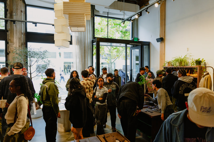 A large crowd of people standing inside a store with overhead lights and dark wood fixtures.