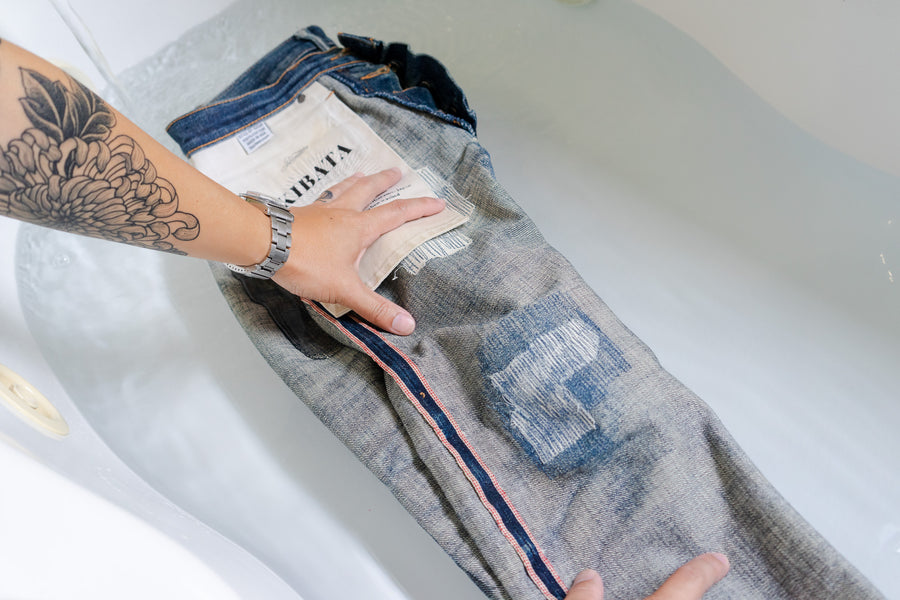 A pair of jeans soaking in a bathtub.