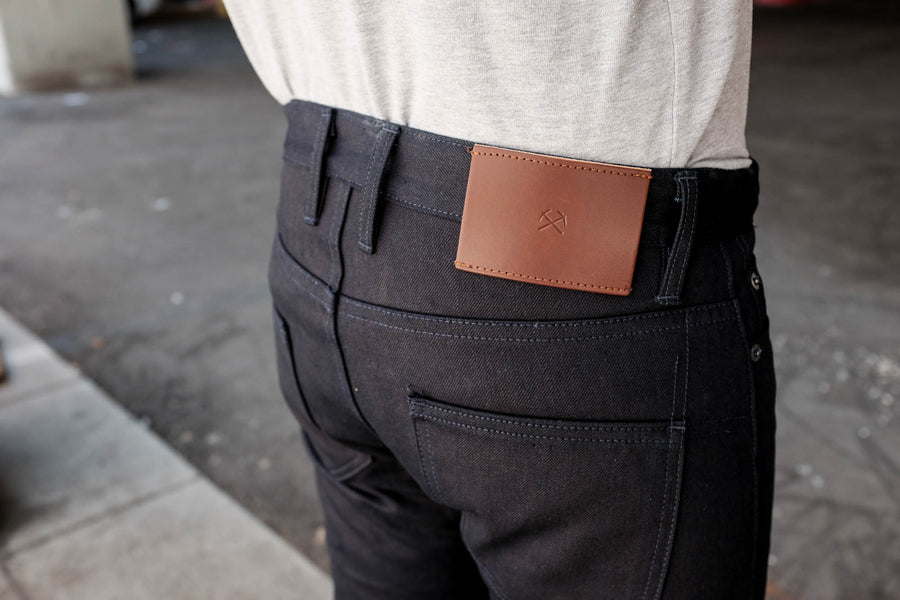 Close up shot of the leather patch featuring the small pickaxe logo on our lightweight 122x denim in shadow 