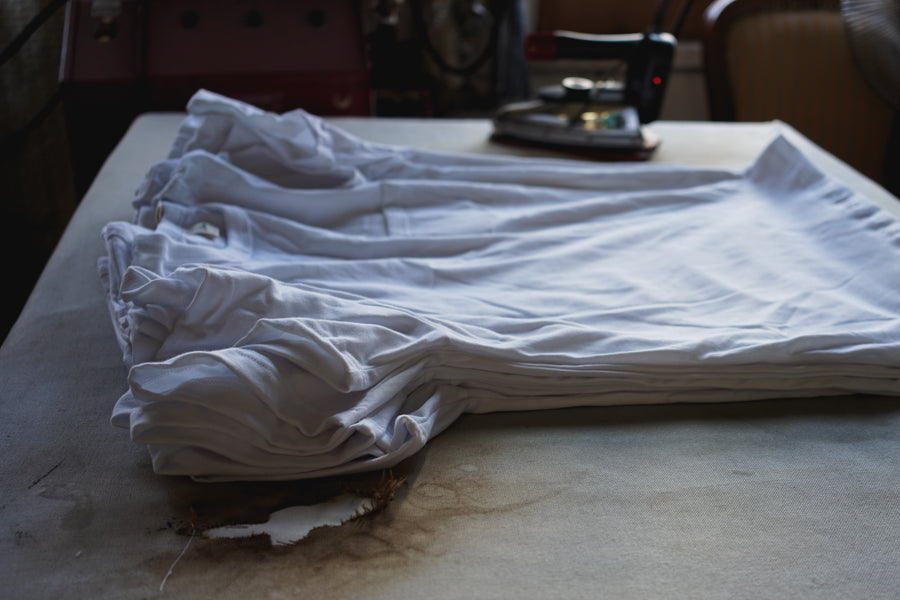 A stack of white t-shirts on a table.