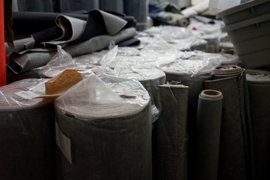 Rolls of uncut denim sit together on a factory floor.