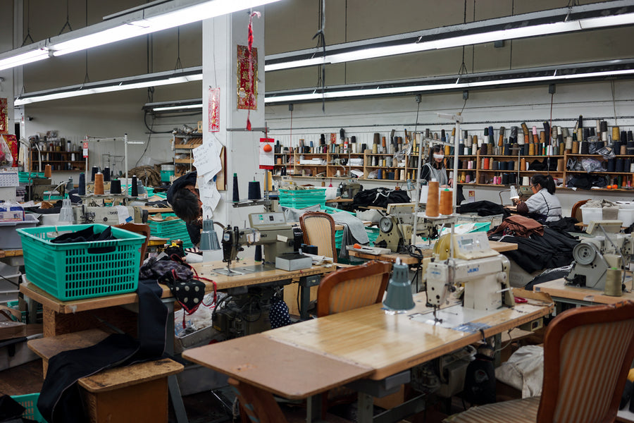 A factory floor, complete with sewing machines, thread and seafoam green bins.