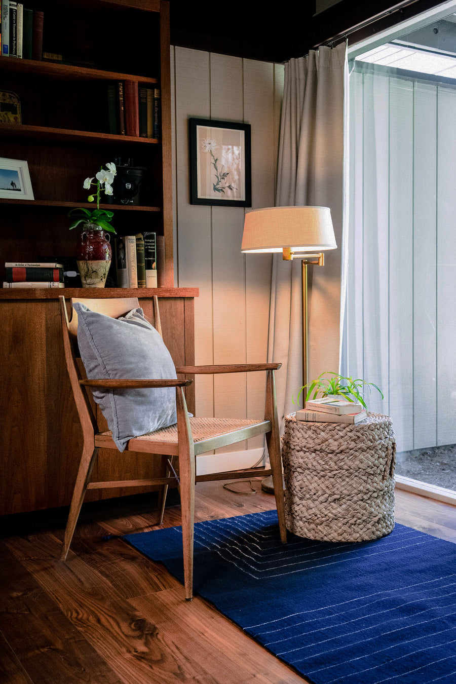 A single chair with a grey pillow sit atop the indigo rug.