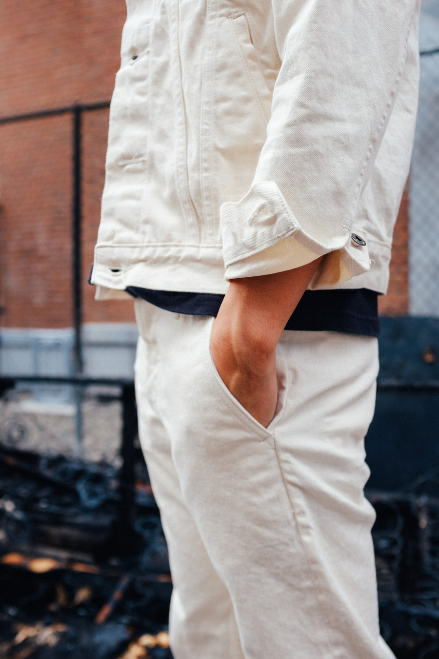A mid-body shot of the natural denim jacket and chinos, with the model's hand in the pocket.