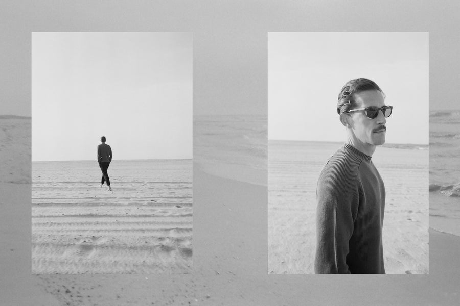 A man in a crewneck sweater and sunglasses looks away.