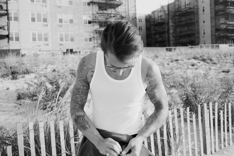 A man in a tank top changes his shirt.