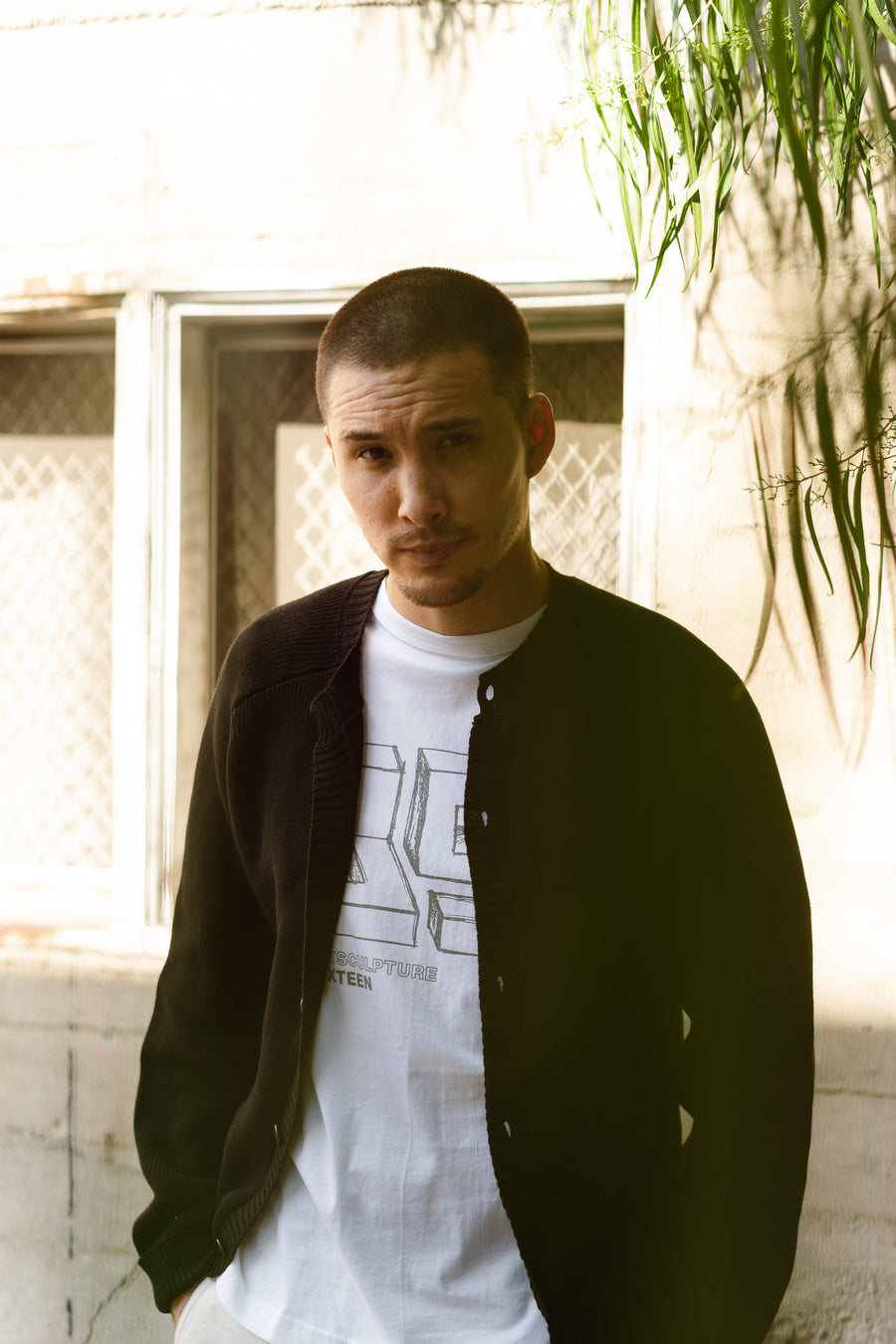 A man wearing a black cardigan and Playscapes graphic tee underneath.