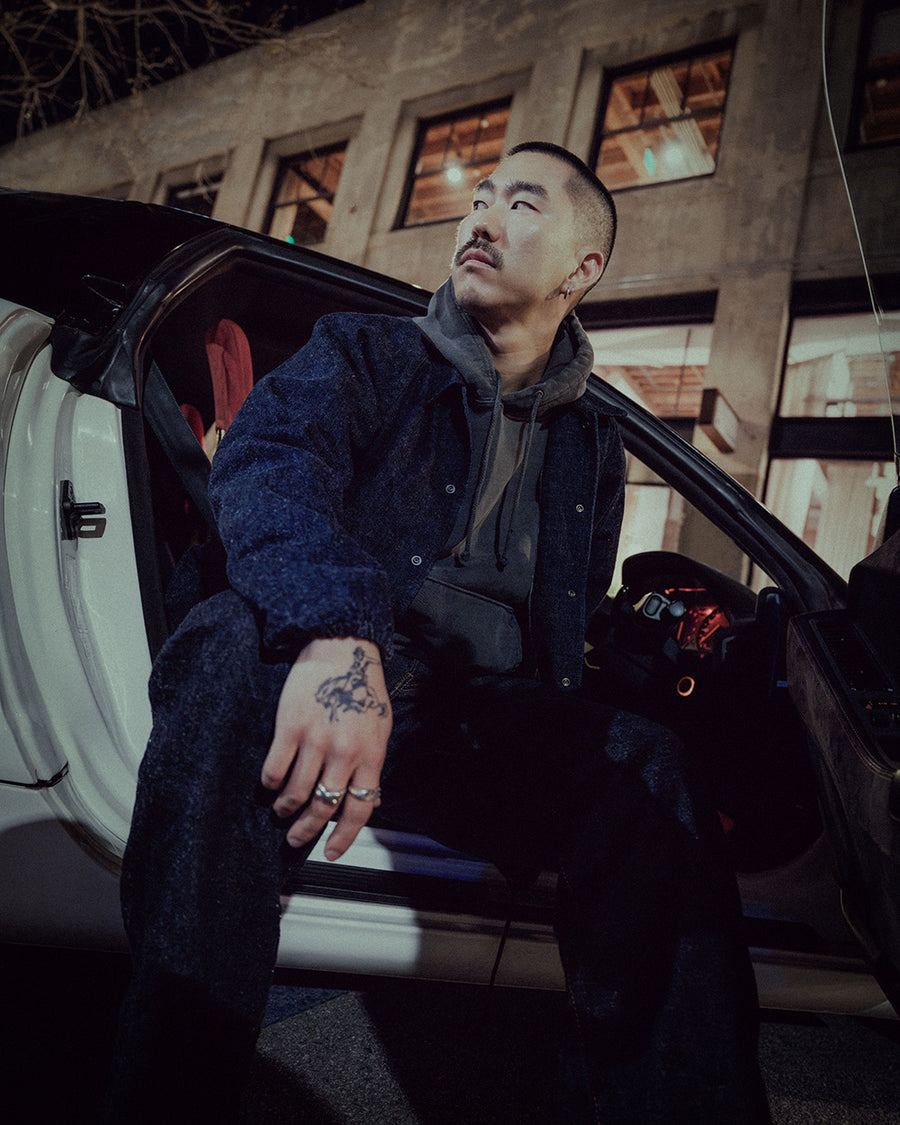 A man sits in the drivers seat of a white sports car.