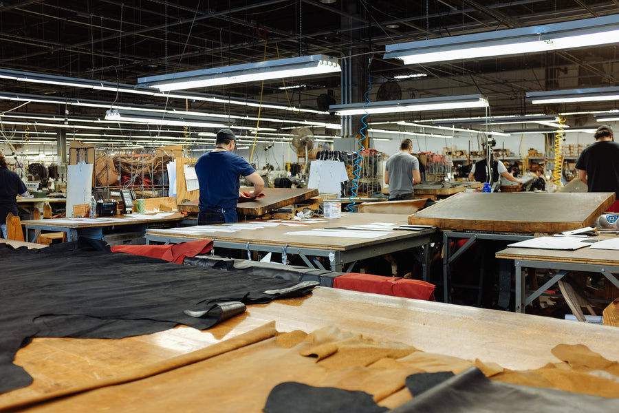 A sea of factory workers labor diligently over leather jackets at the Schott factory at their various stations.