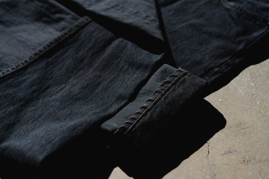An up close photo of overdyed black denim on a concrete floor.