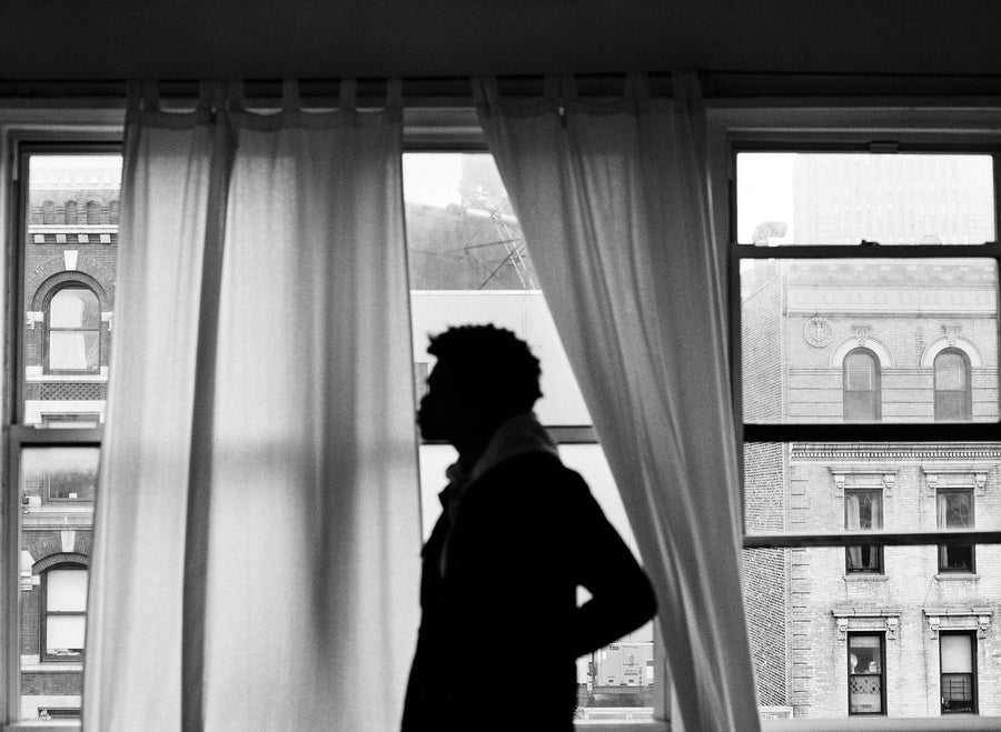 A silhouette of a model standing in front of two curtains blowing in the wind.