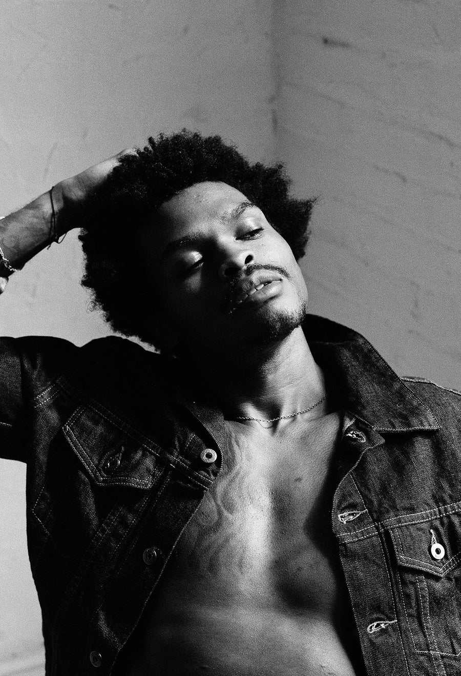 The model runs his hands through his hair as sunlight pours onto his face.