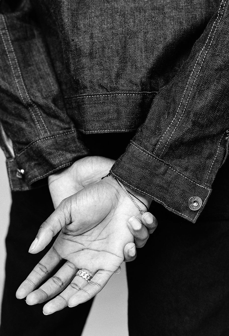 A closeup shot of the model's hands crossed behind his back.