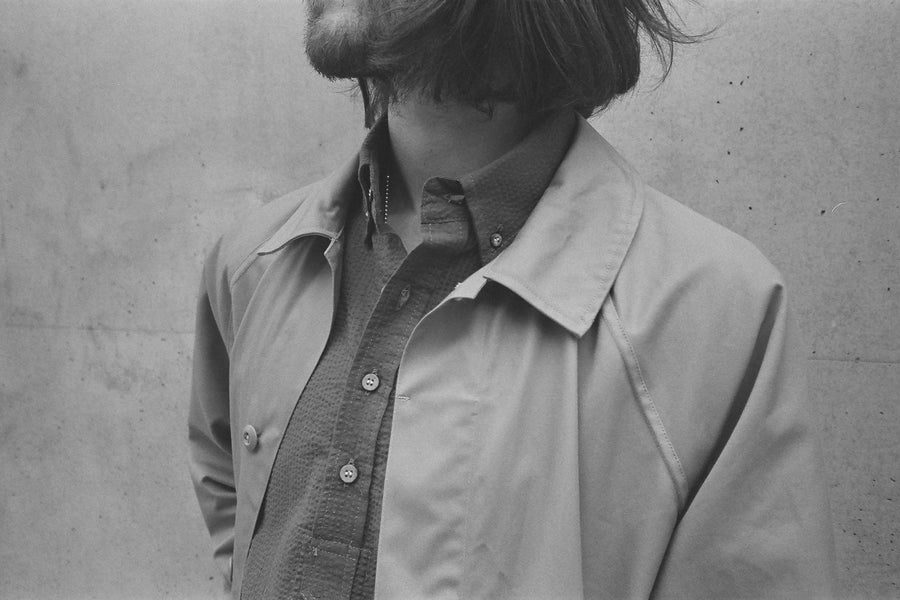 A close up photo of a light colored mac coat and a seersucker shirt.