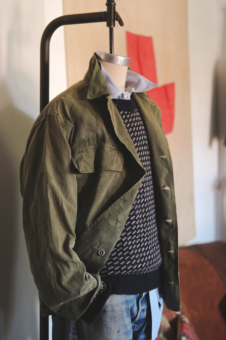 A mannequin sporting a field jacket, a sweater and some faded jeans.