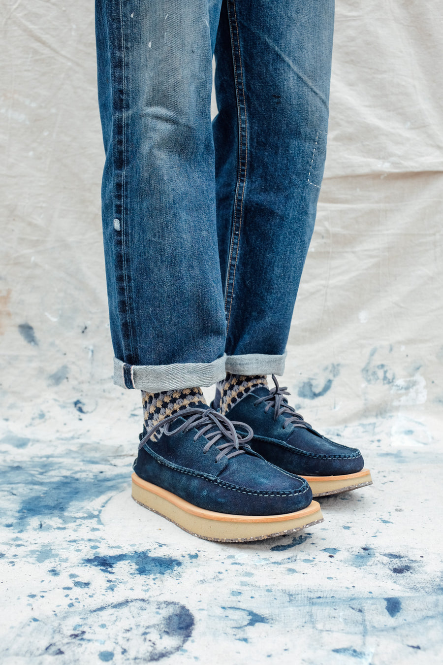 A front 3/4 shot of feet wearing indigo moccasins on an indigo-stained cloth.